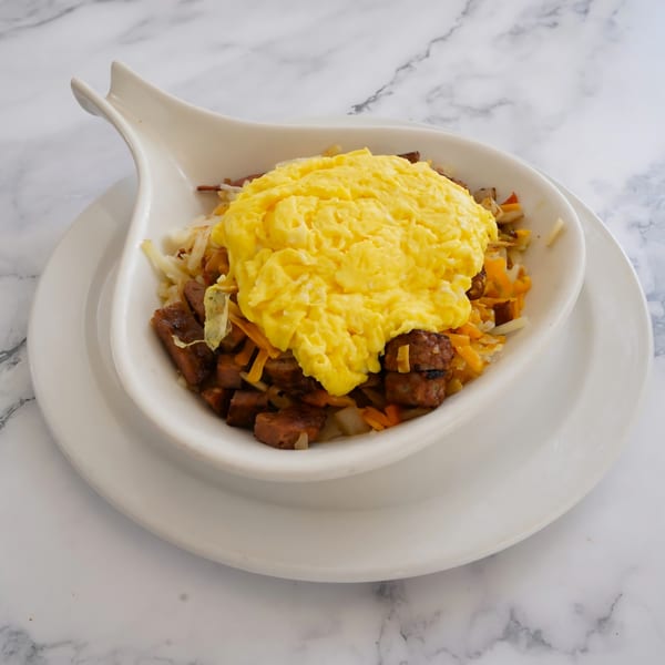 A Grand Rising Cafe breakfast bowl with scrambled eggs, sausage, hash browns, and cheese.