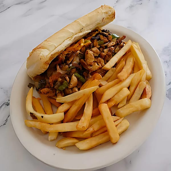 A Grand Rising Cafe cheesesteak sandwich with chicken, peppers, onions, and fries on a white plate.