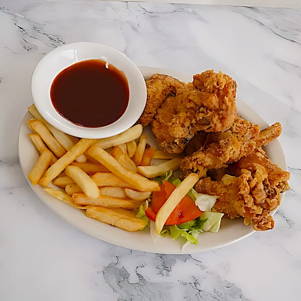 A plate of crispy fried chicken, golden fries, a side salad, and a bowl of dipping sauce.